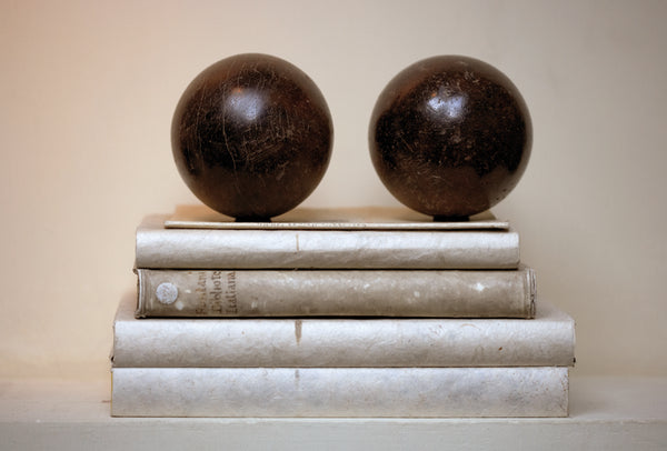 Las bolas de petanca se sientan encima de los libros antiguos con una paleta neutral - Walda Pairon